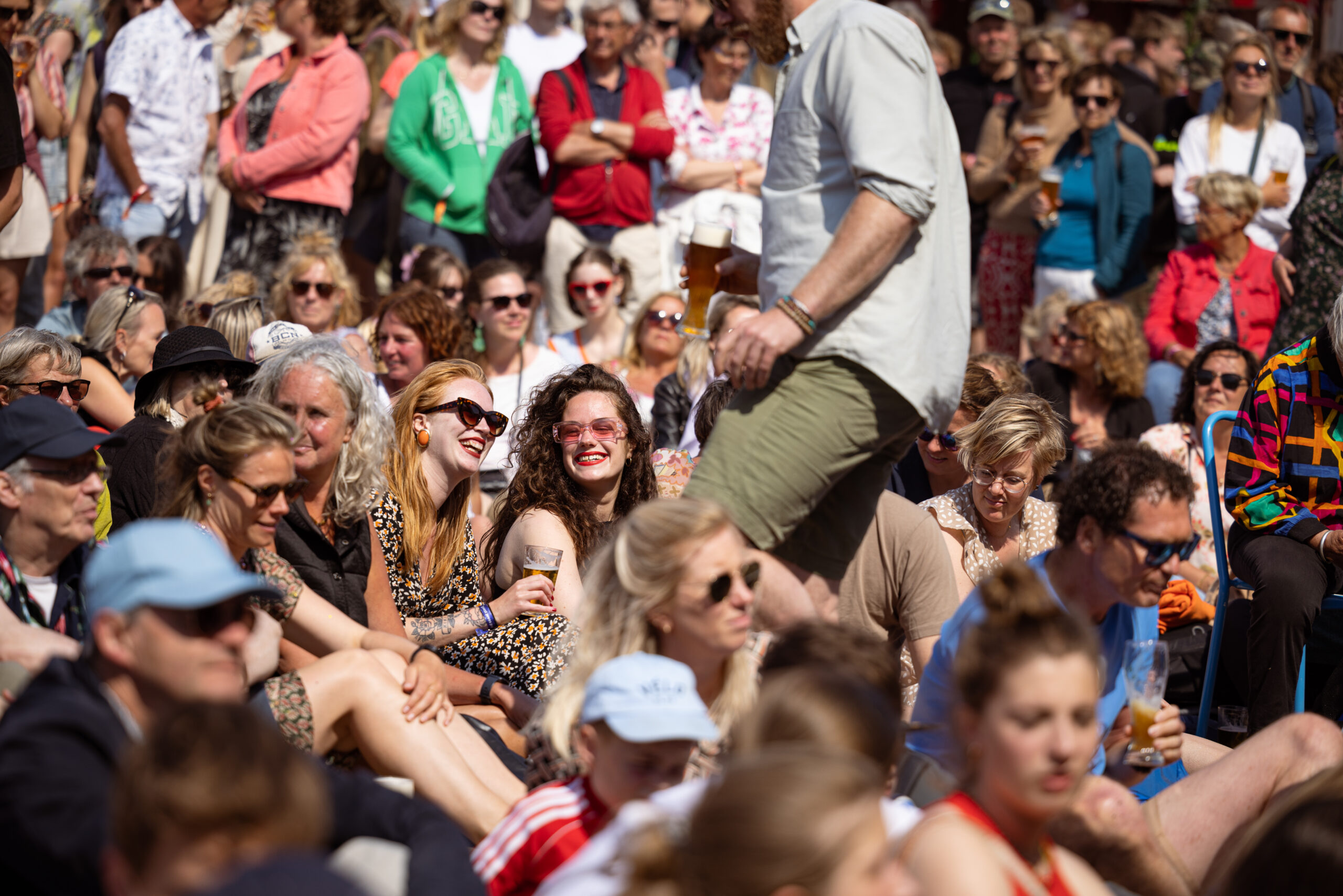Man loopt door zittend publiek op festivalhart de Deining tijdens de opening van Oerol 2023