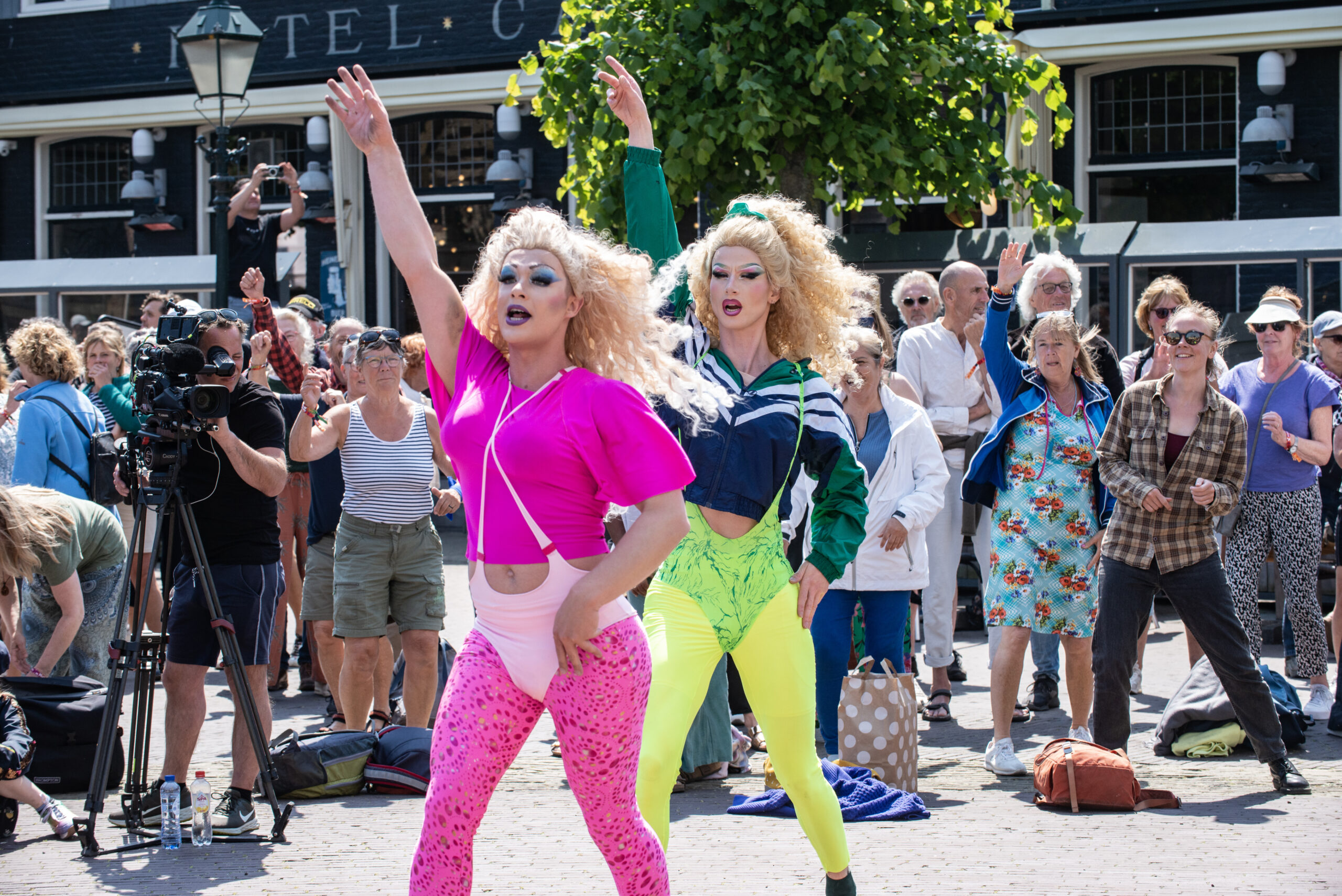 Twee dragqueens in fluoriserende kleding dansen tijdens straattheater in West Terschelling, collectief House of Fitness, Oerol 2023
