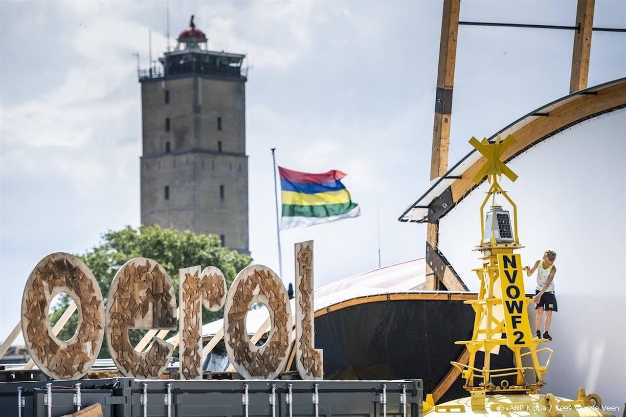 Oerol logo op festivalterrein de Betonning met op de achtergrond de Brandaris en de Terschellinger vlag
