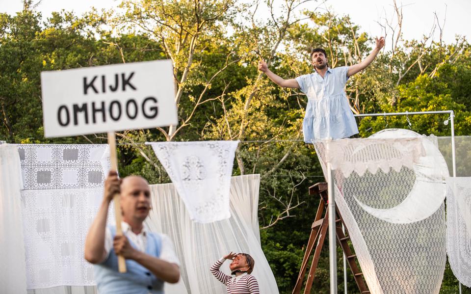 Twee acteurs in in een decor van kanten gordijnen van verschillende lengtes waarbij een acteur een bord omhoog houdt met de tekst Kijk Omhoog, voorstellingsbeeld uit de theatervoorstelling Lorca van Joost Oomen en de Poezieboys tijdens Oerol 2023