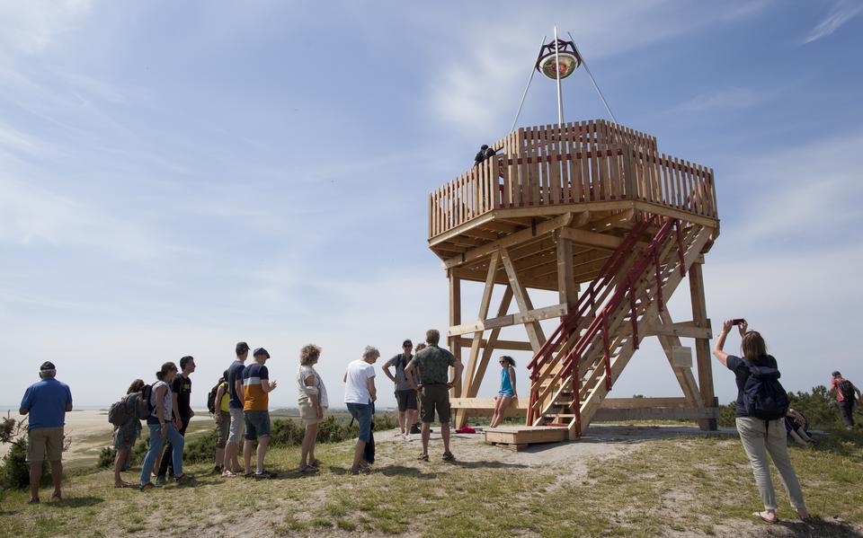 Een groep mensen staan in de rij om de trap te beklimmen naar een achthoekig houten uitkijkpunt als onderdeel van het Expeditie programma van Oerol.
