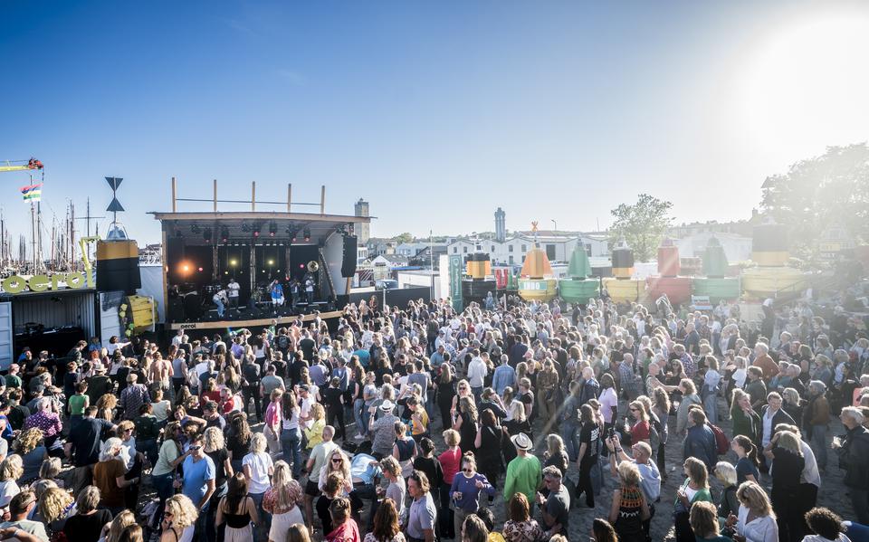 Voormalig festivalterrein de Betonning, omzoomd met grote boeien, staat bomvol mensen die naar een optreden op het grote podium kijken.