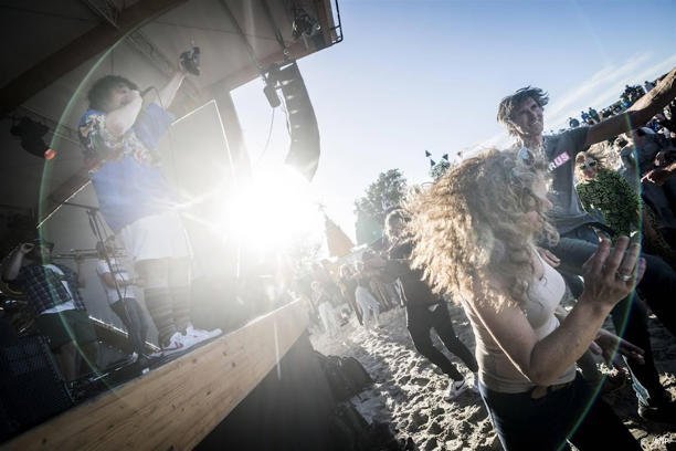 Dansende mensen voor het podium op voormalig festivalterrein de Betonning tijdens Oerol.