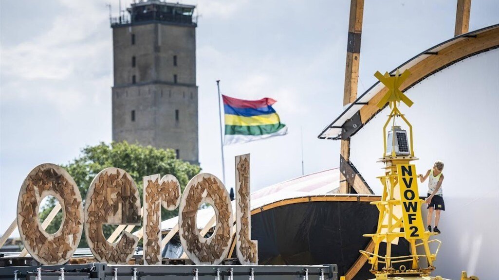 Oerol logo met op de achtergrond de Terschellinger vlag en vuurtoren de Brandaris van Terschelling.