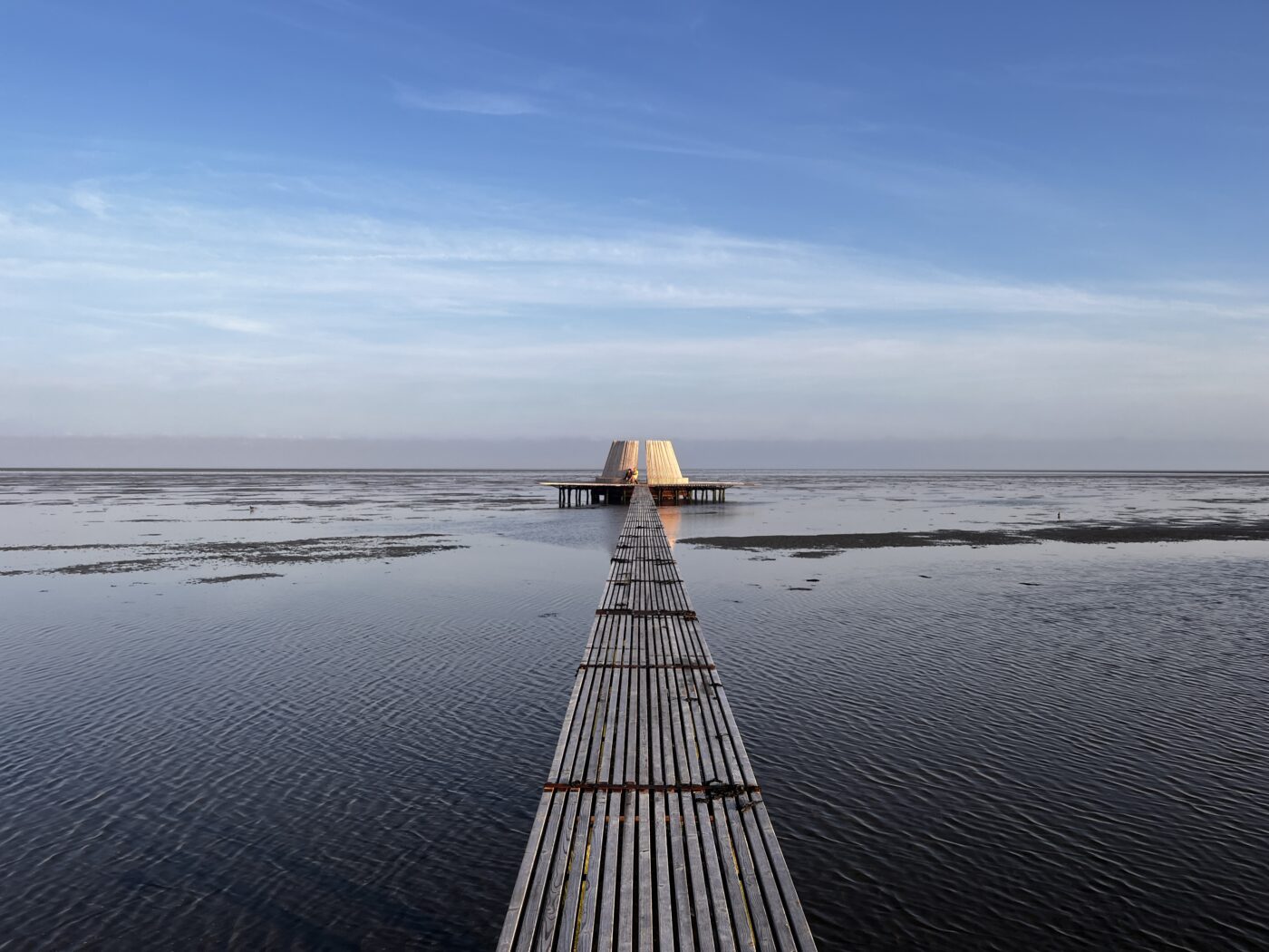 Het houten getijdenobject De Streken van beeldend kunstenaar Marc van Vliet met haar 150 meter lange loopbrug tijdens zonsondergang en laag water, Oerol 2023