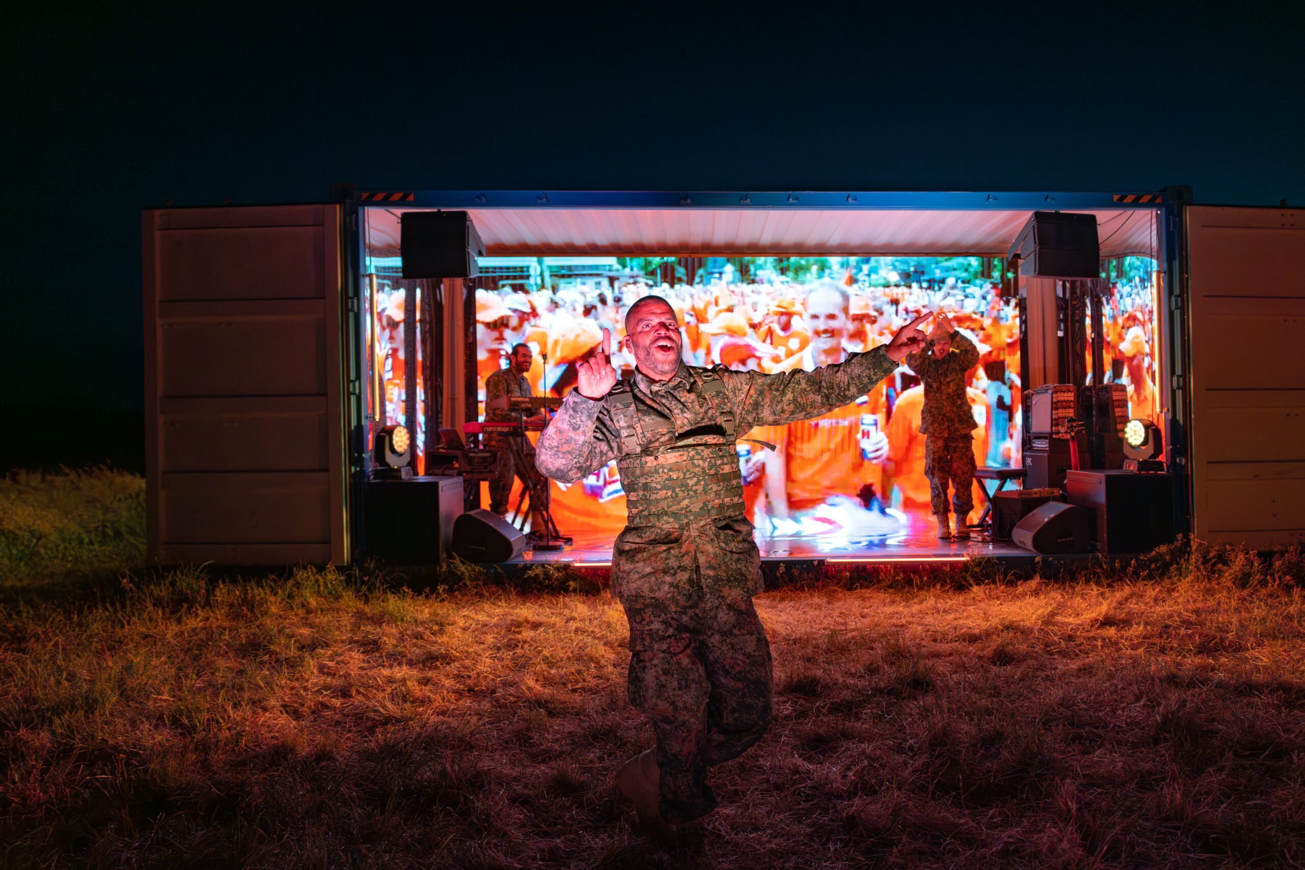 Rapper Sef voor een container met 2 muzikanten en een groot Led-scherm, voorstellingsbeeld van de voorstelling vlag, gespeeld tijdens Oerol 2023.