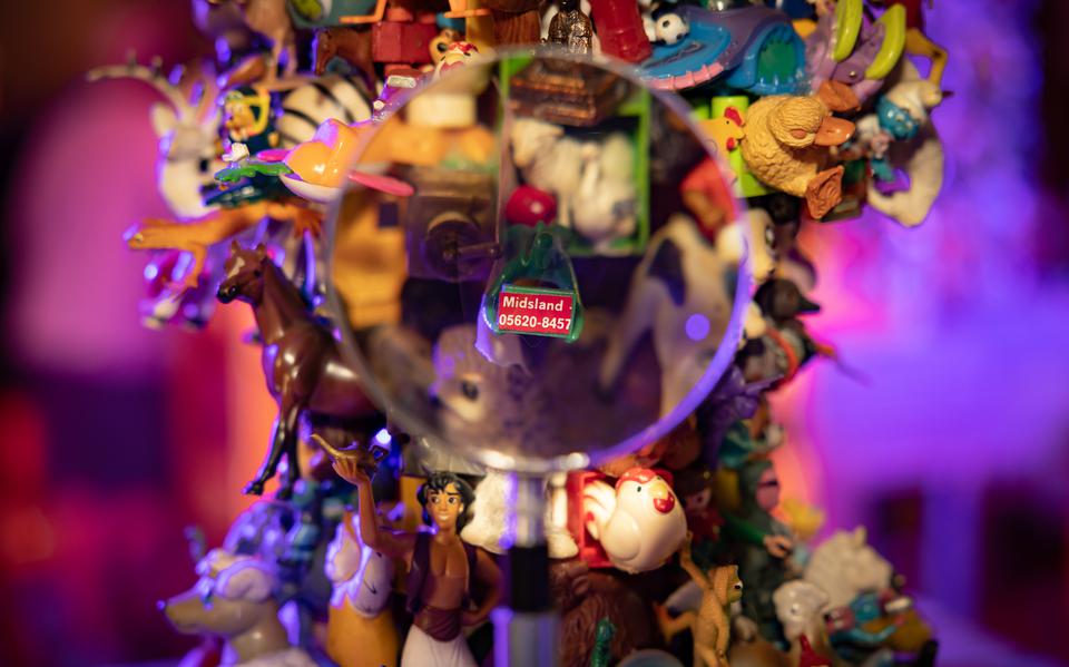 Een vergrootglas toont een vergroting van een Toren van Nienke, torens van ongeveer een meter hoog welke volledig bekleed zijn met speelgoedfiguurtjes, een expositie tijdens Oerol 2023.