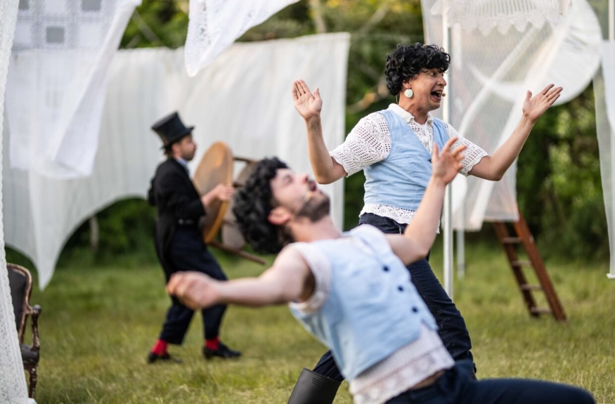 Twee mannen maken grote gebaren tegen een achtergrond van witte doeken, voorstellings beeld uit theatervoorstelling Lorca van Joost Oomen en de Poezieboys, gespeeld tijdens Oerol 2023