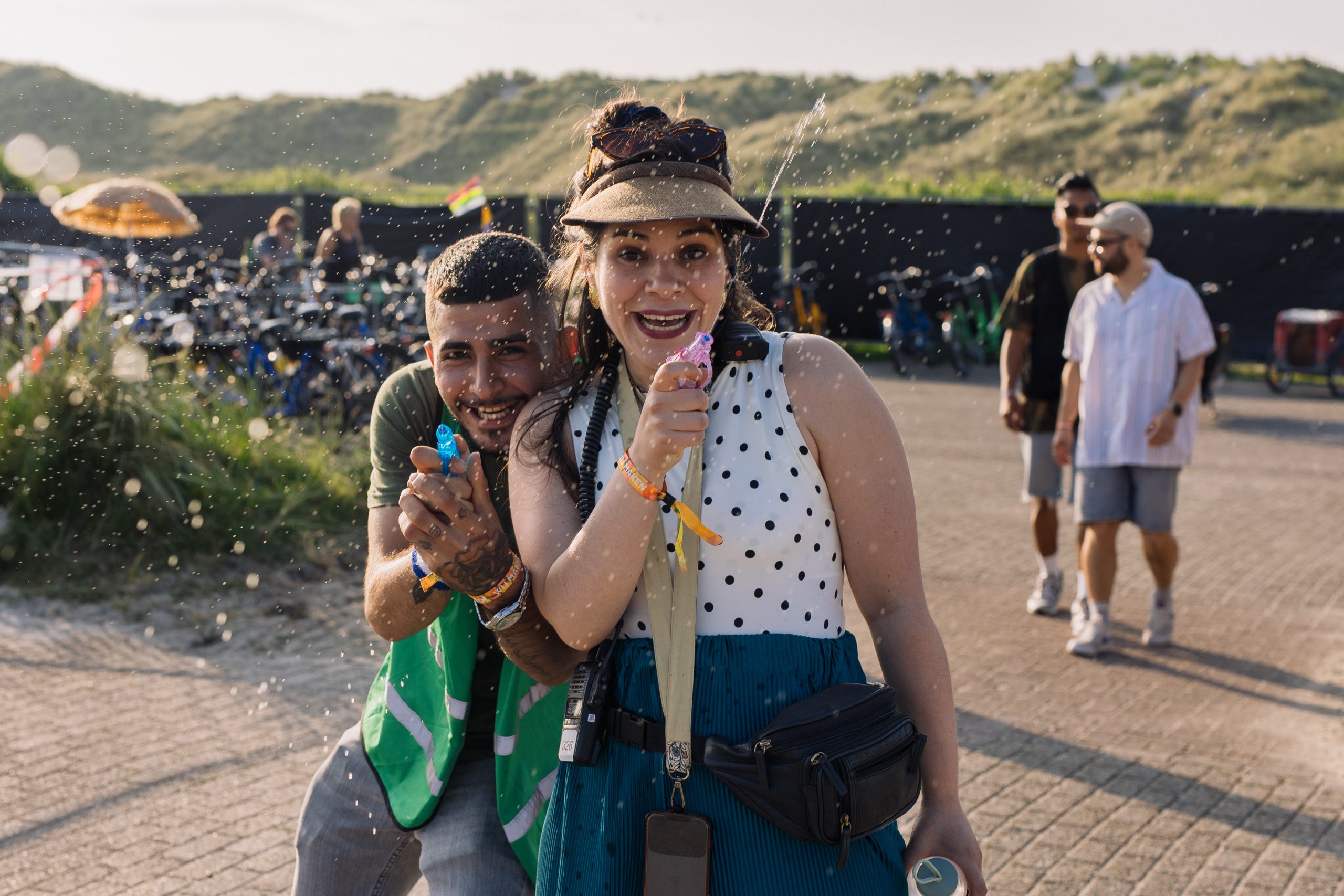twee vrijwilligers spuiten met een waterpistool op de fietsenparkeerplaats van de deining.