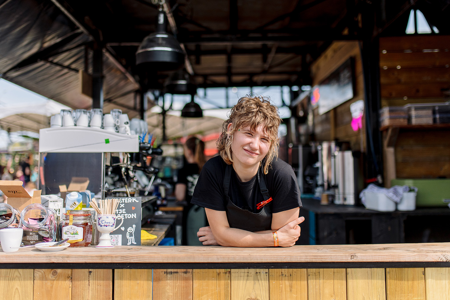 Vrijwilliger leunt over de bar van de koffietent tijdens Oerol 2026